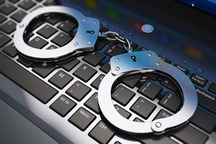 Handcuffs on laptop keyboard - Darren Chaker on Privacy California Self Defense laws and legal principles with handcuffs on laptop representing criminal defense and legal protection