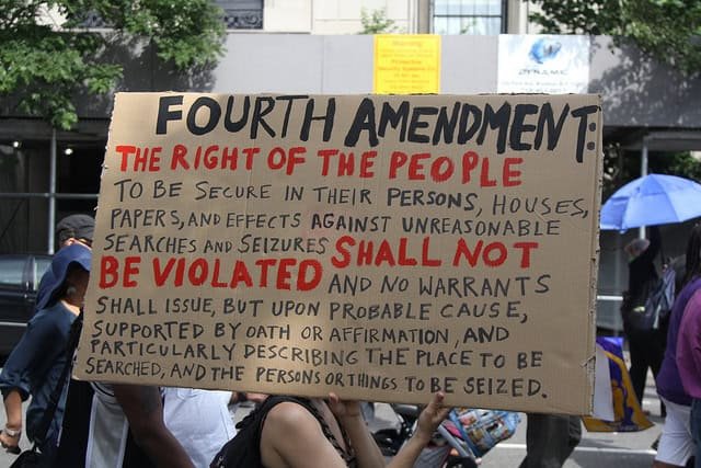 Strip Search and Legal Liability - Darren Chaker on Privacy Article about policies on performing a strip search. Here a protestor holding a sign that reads the significance of the Fourth Amendment rights.